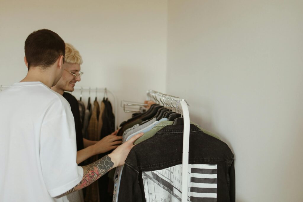 Two adults browsing a clothing rack indoors, reflecting a modern lifestyle and fashion.